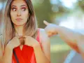 Zaskoczona kobieta z szeroko otwartymi oczami patrzy na wskazujący palec. Wygląda na malkontenta, jakby ktoś ją oskarżył.
