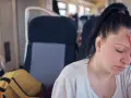 Kobieta w pociągu z ręką na czole, wyraźnie odczuwająca astenia.