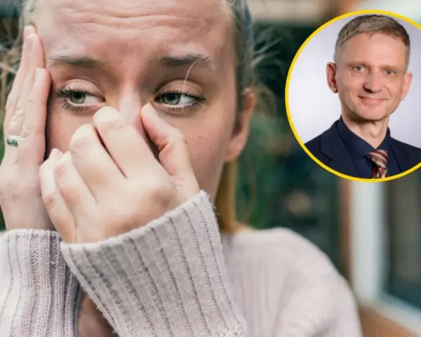 Zmartwiona kobieta z dłońmi na twarzy, jakby walczyła z amnezją. Obok niej uśmiechnięty mężczyzna w garniturze.