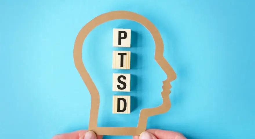W głowie z papieru litery P, T, S, D układają się w słowo PTSD, symbolizując jego objawy.