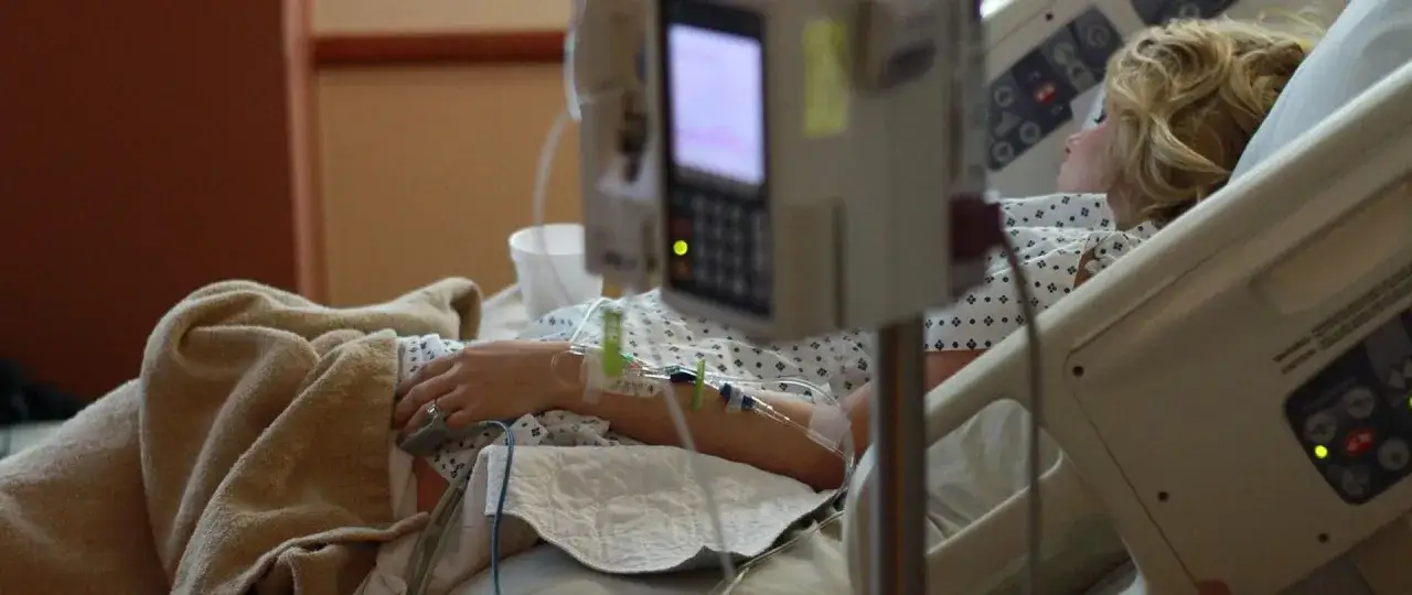 Pacjentka w szpitalu, podłączona do aparatury. W tle monitor, na ręce wenflon. Obraz symbolizuje splątanie w psychiatrii, trudności w zrozumieniu i leczeniu chorób psychicznych.