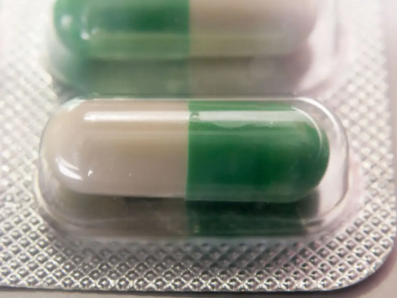 Dwie kapsułki leku Seronil 10 mg w blistrze. Jedna kapsułka jest biało-zielona, druga zielono-biała.