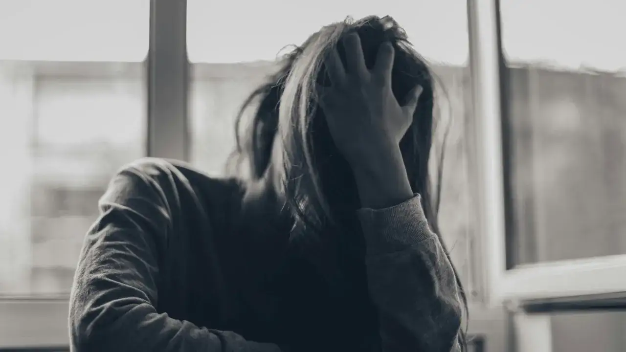 Osoba z ręką na głowie, przygnębiona, przeżywająca epizod depresyjny.