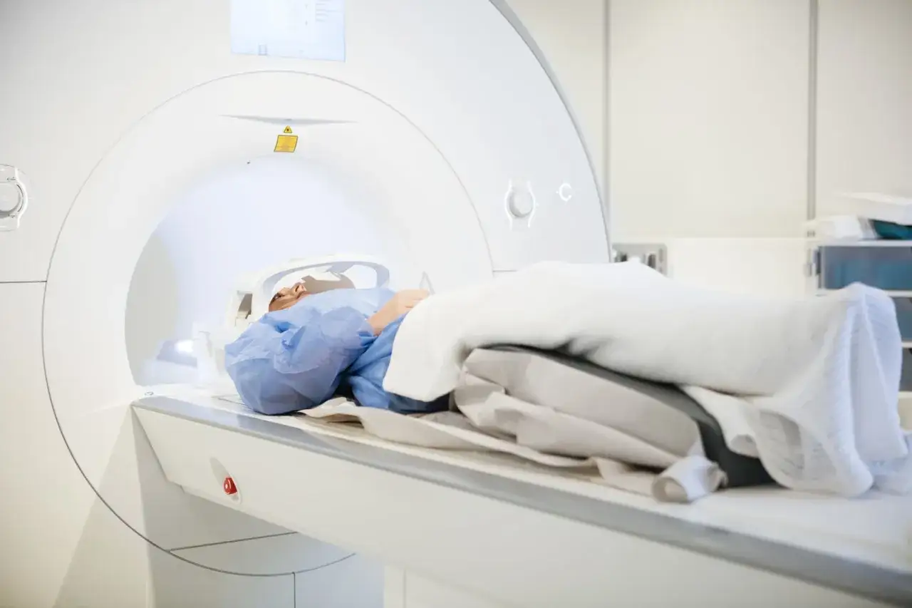 Pacjent w niebieskiej koszuli leży w aparacie MRI, czując narastającą klaustrofobię. Biała, ciasna przestrzeń budzi niepokój.