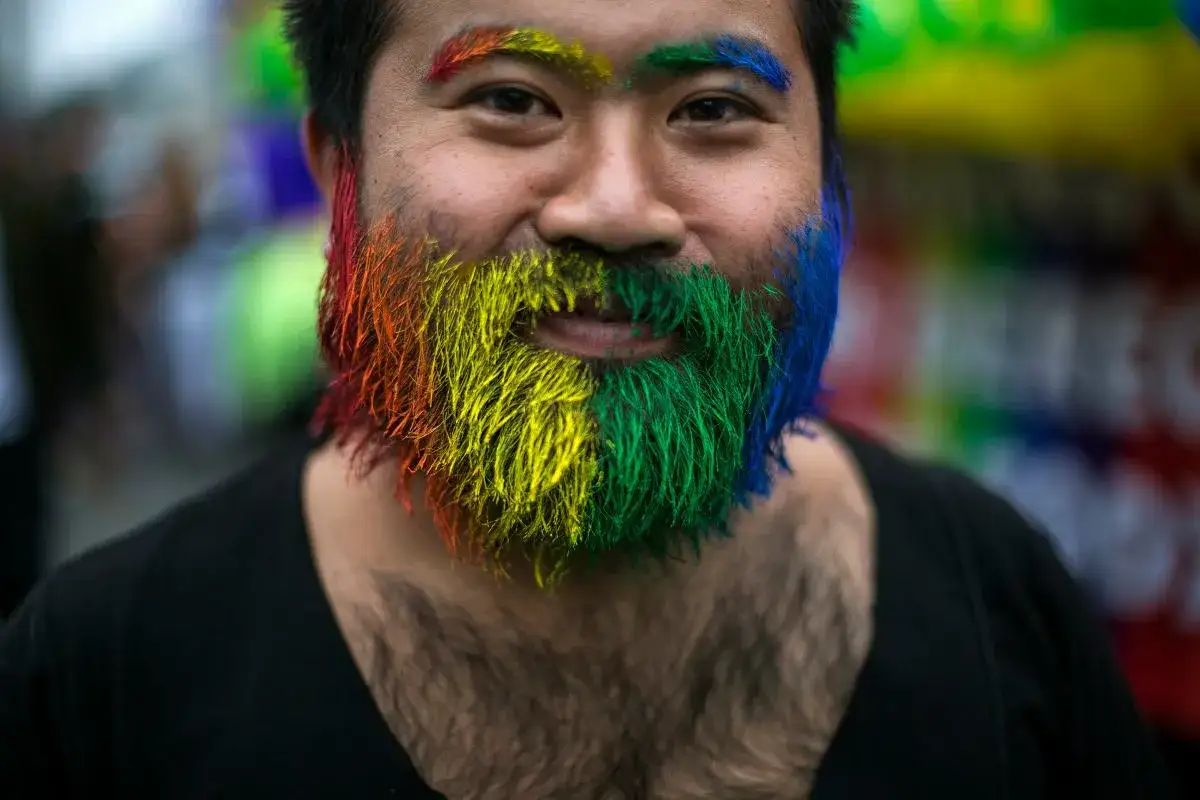 Mężczyzna z tęczowo pomalowaną brodą i brwiami, symbolizujący sprzeciw wobec homofobii.